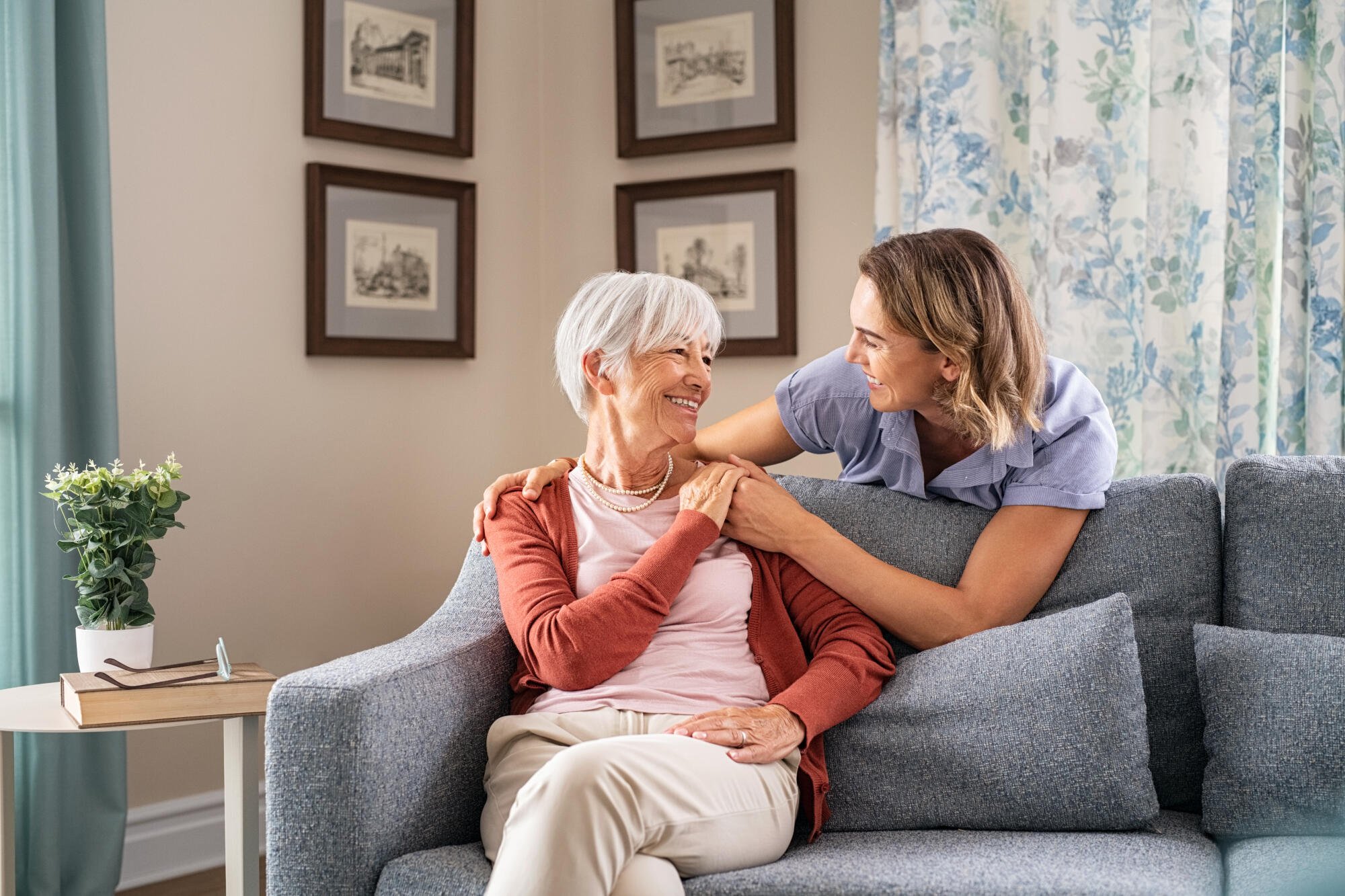 caregiver and resident smiling at each other on a couch